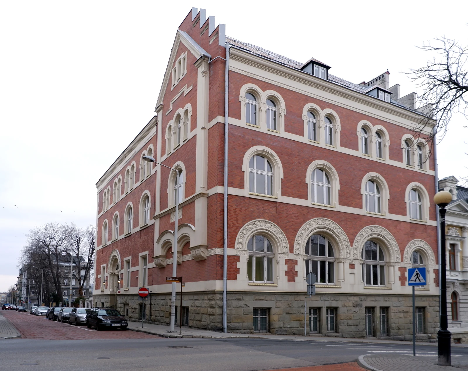 Dom gminy żydowskiej przy Mickiewicza 22: narożny budynek z czerwonej cegły, jasnymi obramieniami okien i schodkowym szczytem.
